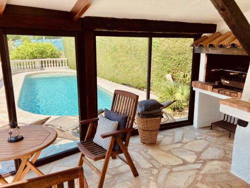 un patio avec une table et des chaises et une piscine dans l'établissement Villa with spectacular views - Pool house with outdoor kitchen and pizza oven, à Auribeau-sur-Siagne