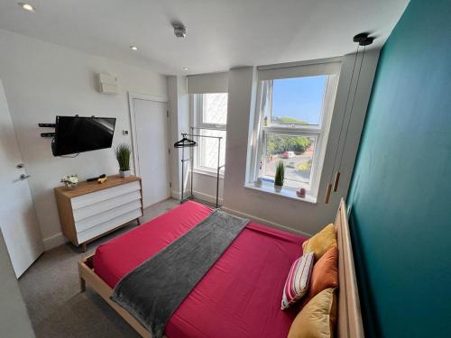 um quarto com uma grande cama vermelha e uma televisão em Born Park em Bournemouth