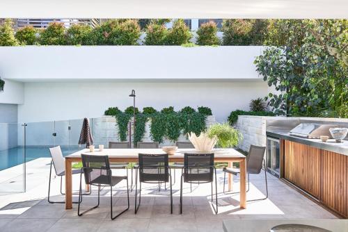 a patio with a wooden table and chairs at Casa Tamarama in Sydney