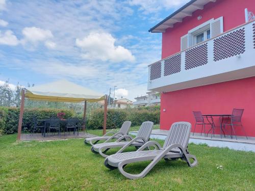 a row of chaise lounges on a lawn next to a pink house at Tuscan Orchard in Montespertoli