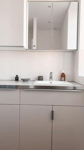 - une cuisine blanche avec un évier et des placards blancs dans l'établissement Gîte Au numéro 13 à 50m de la mer, à La Bernerie-en-Retz