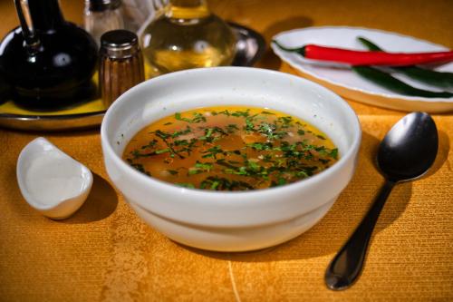 a bowl of soup sitting on a table with spoons at Casa Maria Arges in Piteşti