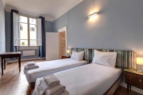 a room with two beds and a desk and a window at Ginori 3P in Florence