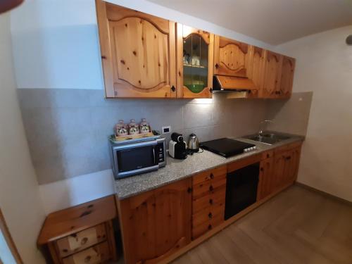 una pequeña cocina con armarios de madera y microondas en Appartamento In Montagna, en Venas
