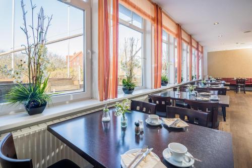 un restaurante con mesas, sillas y ventanas en Strandhotel Achtert Diek, en Langeoog