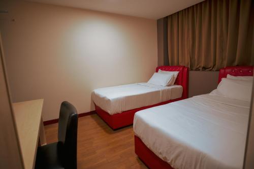 a hotel room with two beds and a desk at Hotel Ambassador @ Bukit Bintang in Kuala Lumpur
