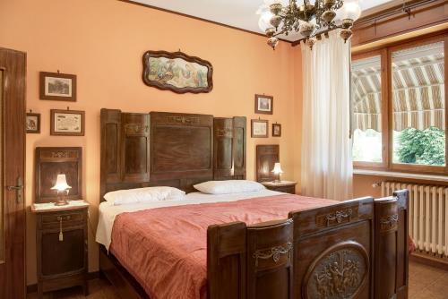 Schlafzimmer mit einem großen Bett mit einem Kopfteil aus Holz in der Unterkunft Clematis in Cisterna dʼAsti