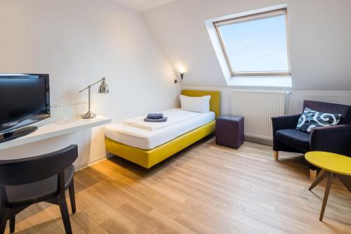 a small room with a bed and a couch and a tv at Strandhotel Achtert Diek in Langeoog