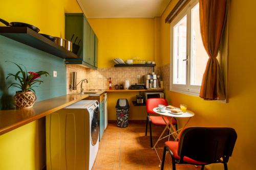 a kitchen with yellow walls and a table and chairs at Geo city center room in Athens