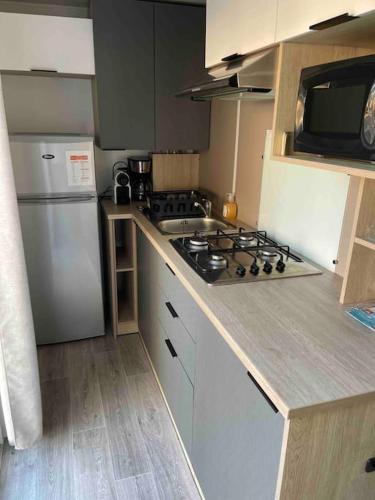 Il comprend une petite cuisine équipée d'une cuisinière et d'un réfrigérateur. dans l'établissement Mobil-Home Camping 5* Montalivet, à Vendays-Montalivet