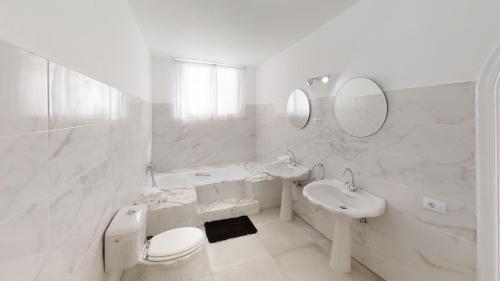 a white bathroom with a toilet sink and mirror at Villa las Buganvillas MASPALOMAS - Cocina y habitaciones con baños privados in Maspalomas