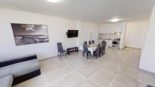 een woonkamer met een tafel en stoelen en een keuken bij Villa las Buganvillas MASPALOMAS - Cocina y habitaciones con baños privados in Maspalomas