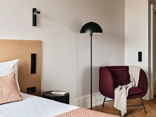 a bedroom with a bed and a chair and a lamp at Hoppen House Apartamenty w centrum miasta in Radom