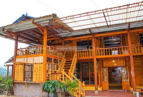 a large wooden building with a staircase in front of it at A Phủ Home’s in Bắc Yên