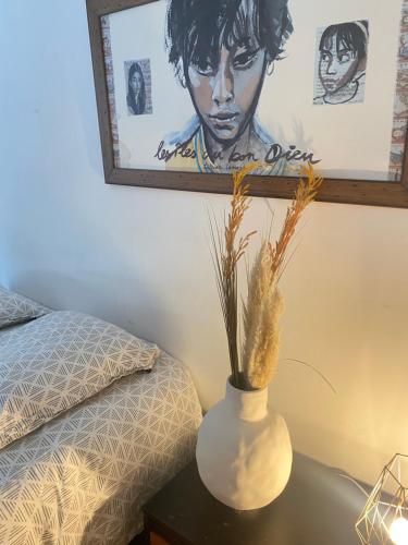 um vaso branco sentado numa mesa ao lado de uma cama em Chambre privée avec SDB attenante em Vertou