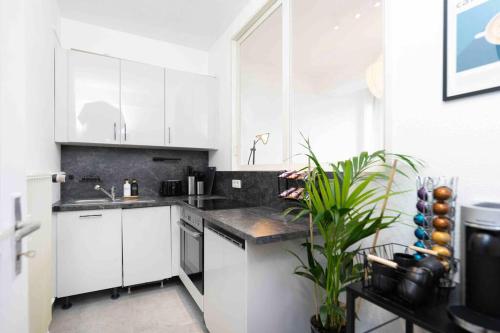 una cucina bianca con armadi bianchi e lavandino di Comfy Apartment Heart of Mannheim a Mannheim