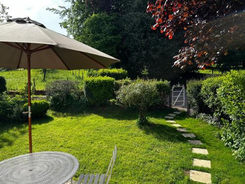 einen Tisch mit einem Regenschirm im Hof in der Unterkunft Cottage Vesqueville in La Hoguette
