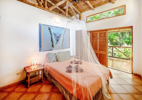 a bedroom with a bed with a mosquito net at Private Villa on 2-Acres of Jungle Garden & Pool in Manzanillo