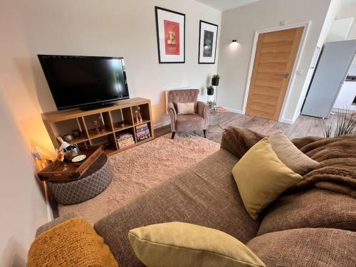 ein Wohnzimmer mit einem Sofa und einem Flachbild-TV in der Unterkunft *BRAND NEW* Luxury Country Lodge in Burnham on Crouch