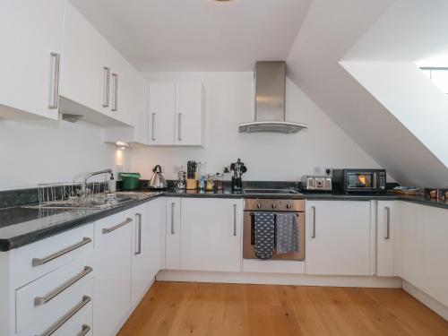 an attic kitchen with white cabinets and appliances at Number 10 The Penthouse in Swanage