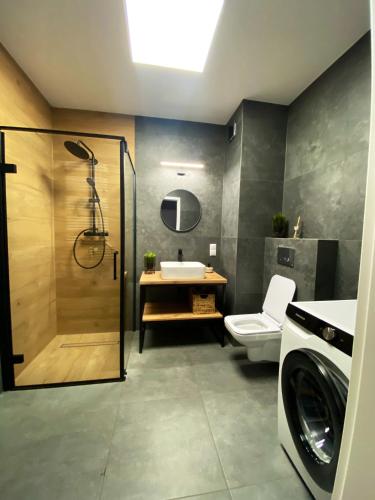 a bathroom with a shower and a toilet and a sink at Apartament Sanok nad stawami in Sanok