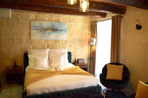 a bedroom with a large bed and a chair at Babel Suites in Valletta