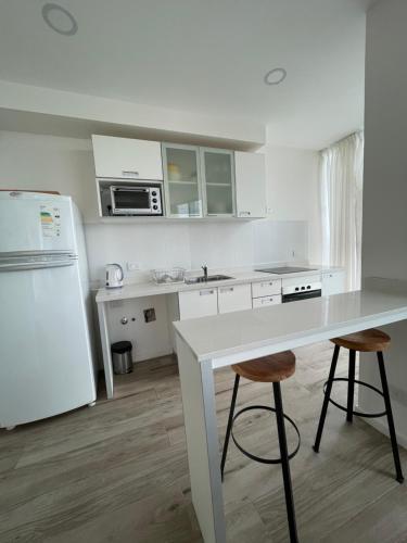 a white kitchen with a table and two stools at Departamento Puerto in Santa Fe