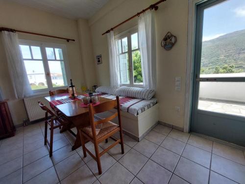 a dining room with a table and two windows at Palaiokrassa sunny appartment in Andros