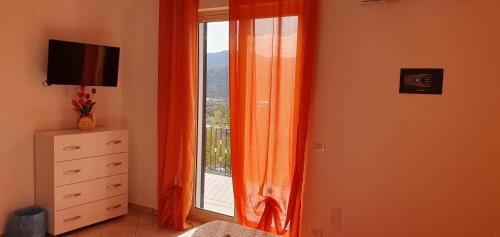 1 dormitorio con ventana y cortina naranja en MARE NATURA, en Patti