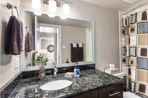 a bathroom with a sink and a large mirror at Superb 2 bedroom downtown with river view in Saskatoon