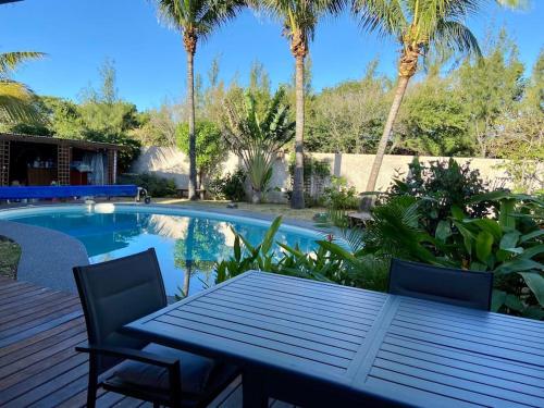 un patio avec une table et des chaises à côté d'une piscine dans l'établissement Très belle villa,piscine chauffée, jacuzzi,hammam., à Étang-Salé les Bains