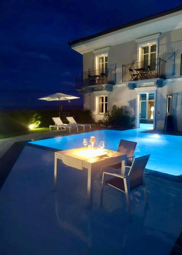 a white table and chairs next to a swimming pool at night at Villa Nonna Cicci Boutique Hotel - SPA in Cisterna dʼAsti