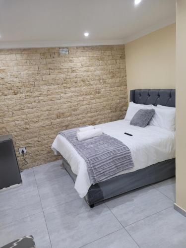 a bedroom with a large bed and a brick wall at MIRAJO Guest House in Cape Town