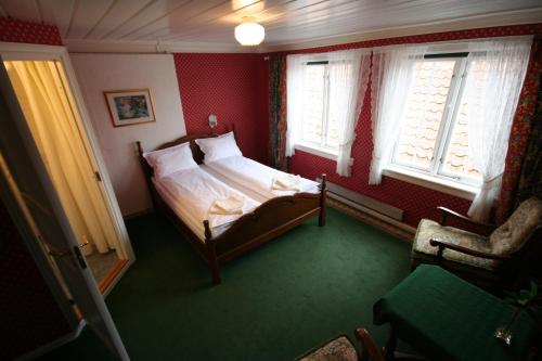 a bedroom with a bed and a chair and windows at Norneshuset Overnatting in Skudeneshavn