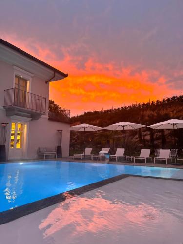 a villa with a swimming pool with a sunset at Villa Nonna Cicci Boutique Hotel - SPA in Cisterna dʼAsti