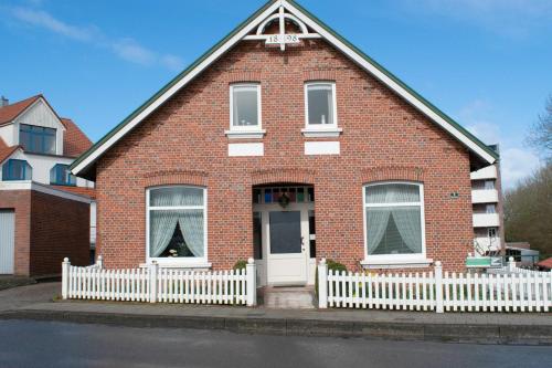 a red brick house with a white fence at das Fischerhus in Bensersiel