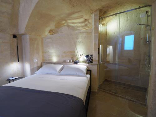 a bedroom with a bed and a glass shower at Dimore dei Mercanti in Matera