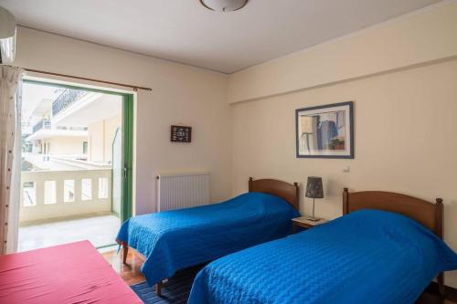 um quarto com duas camas com lençóis azuis e uma janela em Spacious 3bedroom Apartment Nafplion em Nafplio