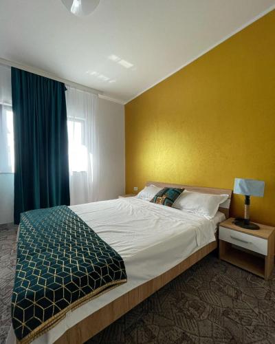 a bedroom with a large bed with a yellow wall at BLACK SEA HOUSE in Vama Veche