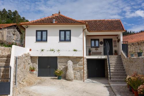 a white house with black garage doors and stairs at Casa de Gonçalo in Pinheiro