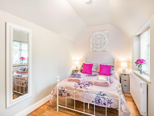 a bedroom with a bed with pink pillows and a mirror at Pittendrigh Cottage in Briston