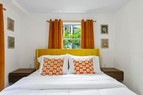 a bed with orange and white pillows and a window at That 70’s Themed Apt Close to Coffee, Food + Shops in Tampa