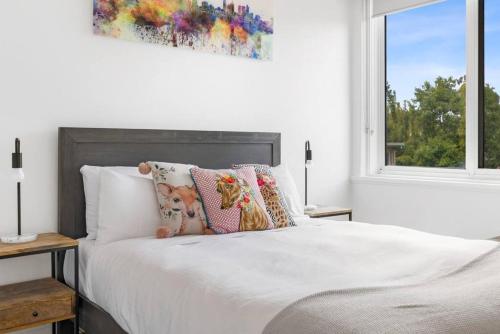 a white bedroom with a bed with pillows and a window at South Yarra apartment with stunning views in Melbourne
