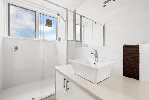 a white bathroom with a sink and a shower at South Yarra apartment with stunning views in Melbourne