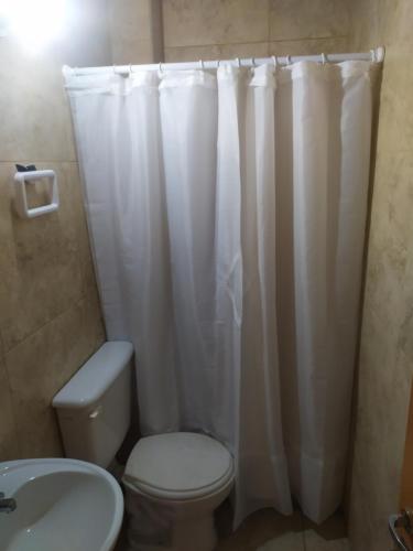a bathroom with a toilet and a white shower curtain at Departamentos Anchorena #6 in Ciudad Lujan de Cuyo