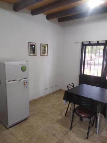 a kitchen with a table and a refrigerator in a room at Departamentos Anchorena #6 in Ciudad Lujan de Cuyo