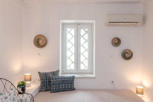 a white living room with a window and pillows at Chora 5 - Central Rooms by TinosHost in Tinos Town