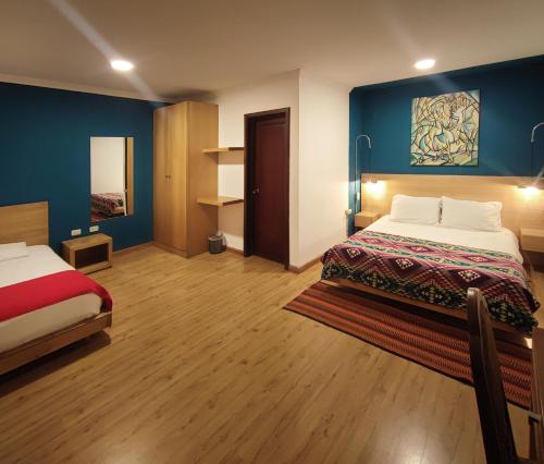 a hotel room with two beds and blue walls at Hotel Casa Merced in Cuenca