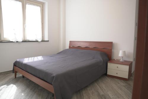 a bedroom with a bed and a nightstand and two windows at L'ANGOLO VERDE in Cascina