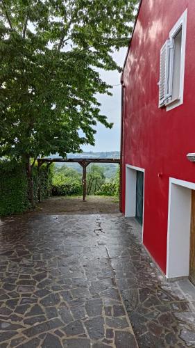 a red building with a stone walkway next to a tree at Tuscan Orchard in Montespertoli
